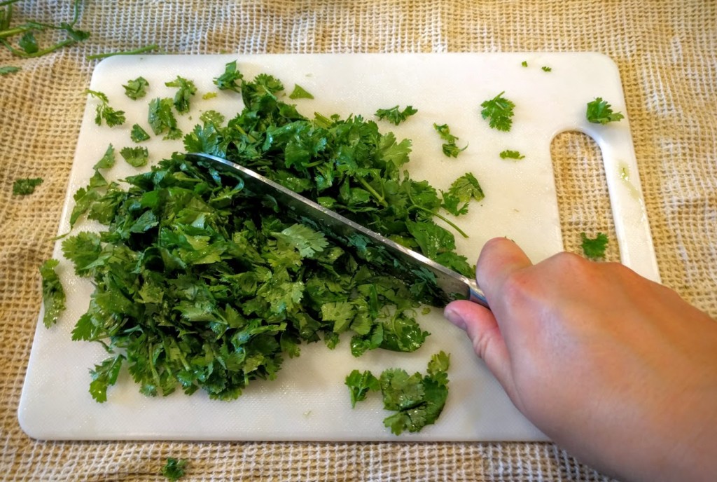 cutting board with a knife cutting parsley