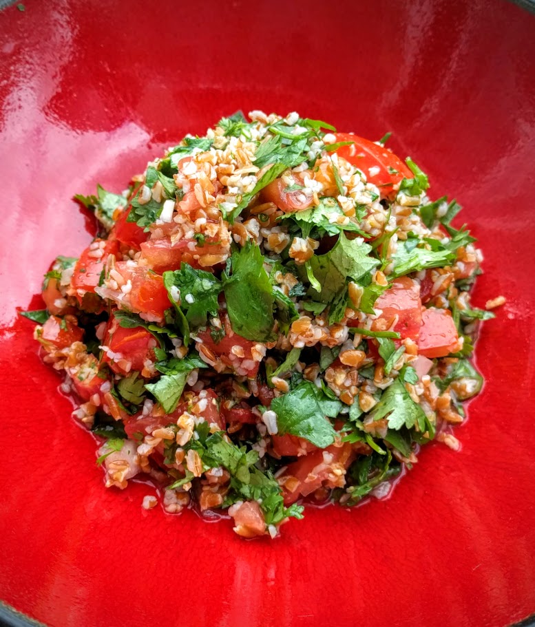 red bowl with green giraffe tabouleh salad in it